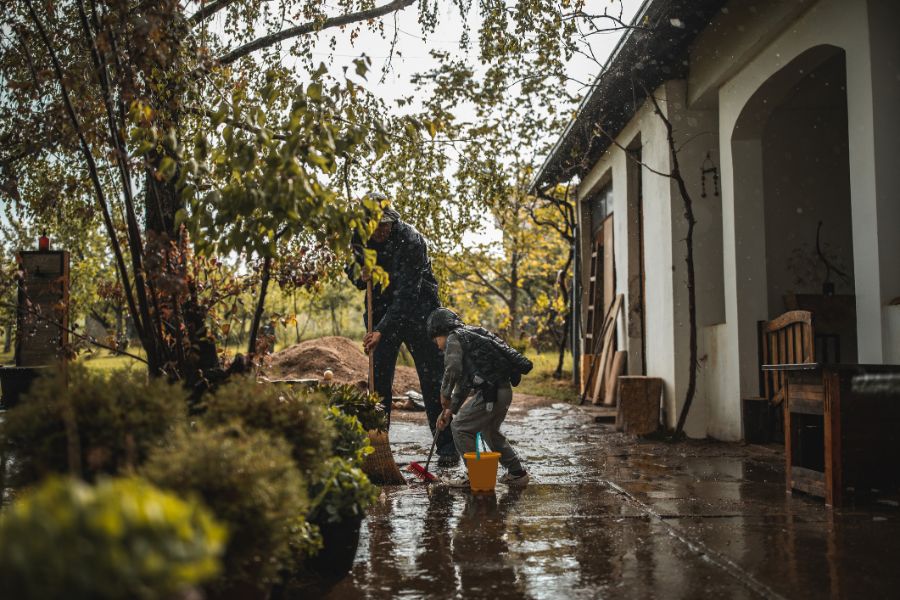 a father and his child cleaning the outside part of their house after a flood