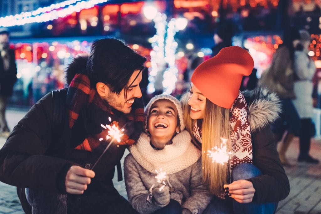 a family holding a sparkle with winterfest background
