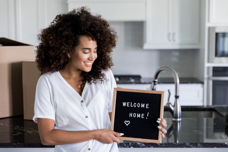 women holding a letter board that says welcome home