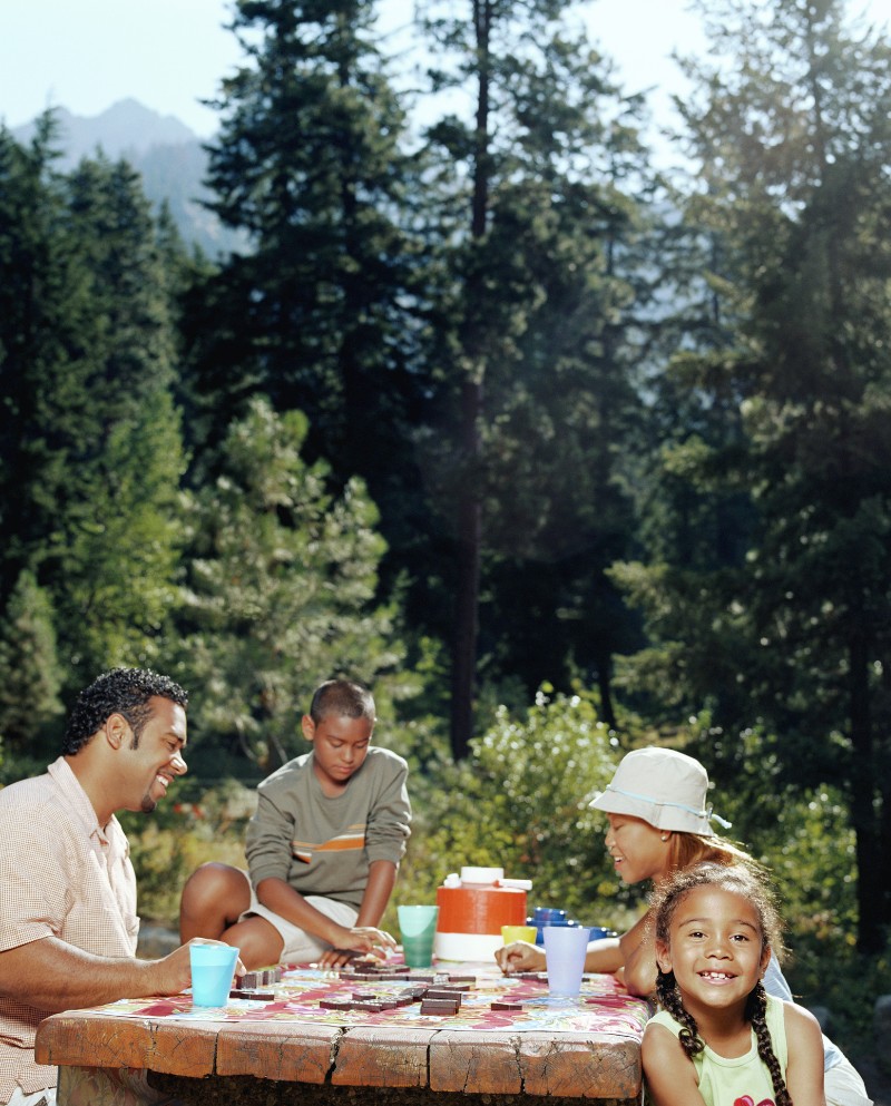 a family playing dominoes at a picnic table