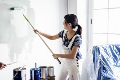 A woman painting the wall white