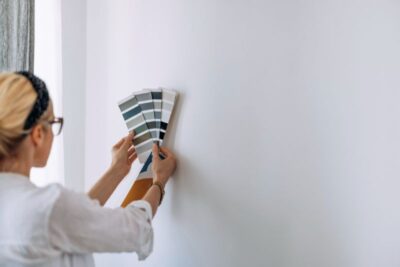 young woman holding colour chart on white wall